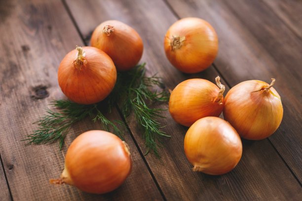 深色天然木材制成的桌子上放着洋葱图片下载