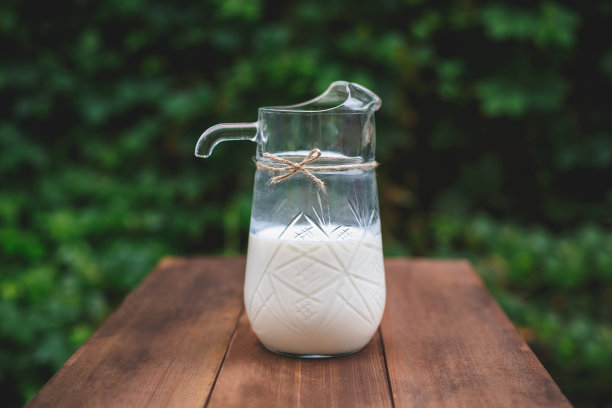 牛奶在木桌上的罐子里，颜色很深图片下载