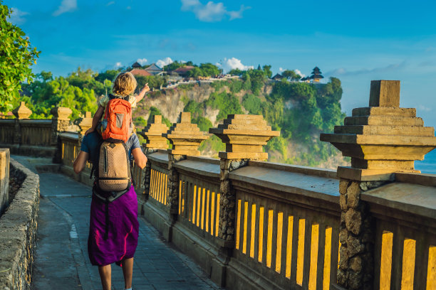 一对父子在印尼巴厘岛的Pura Luhur Uluwatu寺庙旅行。令人惊叹的景观-悬崖与蓝天和大海。和孩子一起旅行的概念图片下载