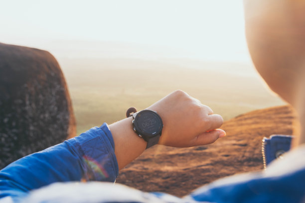 在清晨日出的背景下，年轻的亚洲女性在智能手表上监视自己的进展。锻炼和放松图片下载