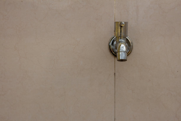 不锈钢水龙头，固定在建筑外墙的瓷砖上。图片下载