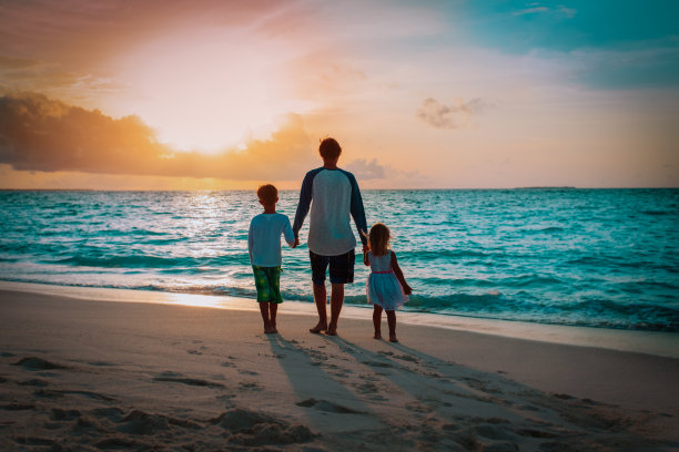 日落时分，父亲和孩子们在海滩上散步图片下载