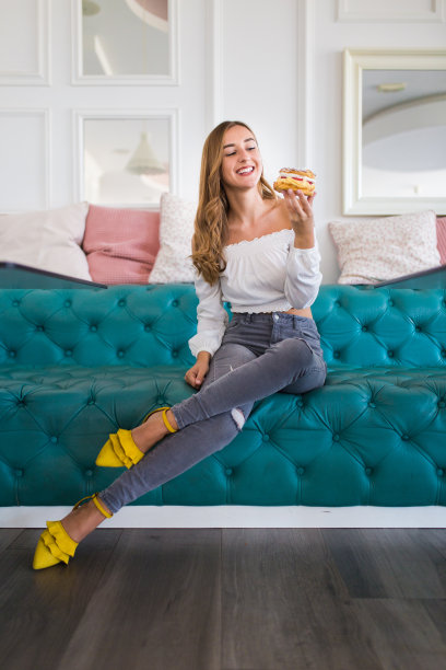 年轻漂亮的女人在自己的蛋糕店吃甜甜圈图片下载