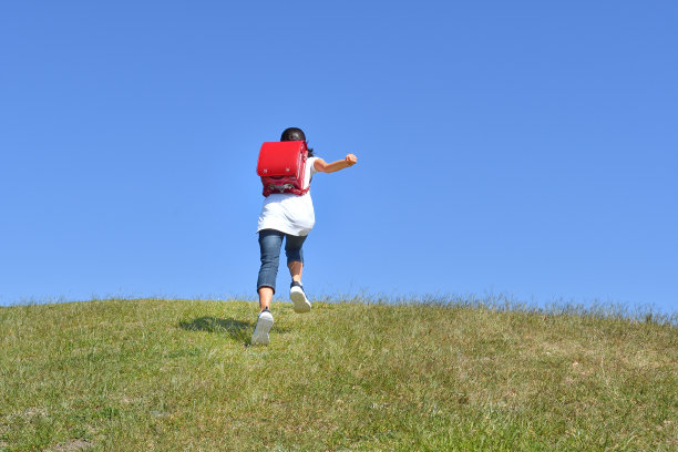 日本小学女孩在蓝天下奔跑的背影图片下载