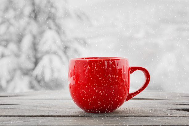 特写咖啡杯在桌子上对着冬天的风景。图片下载
