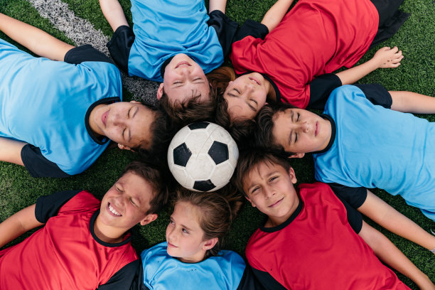 足球队的孩子们躺成一圈，中间放着一个足球图片下载