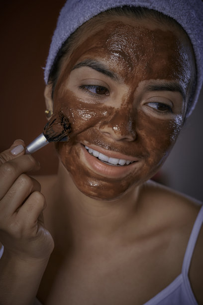 近距离的西班牙年轻女子在洗澡后敷巧克力面膜在她的脸上图片下载