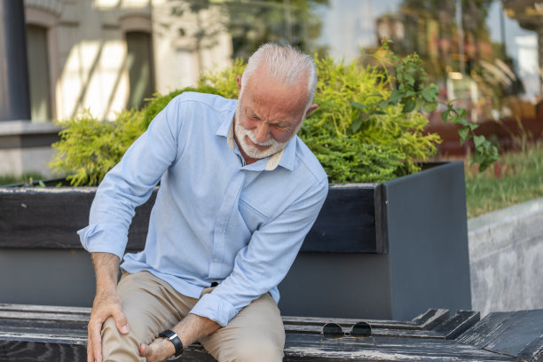 在城市街道上有膝盖问题的资深商人图片下载