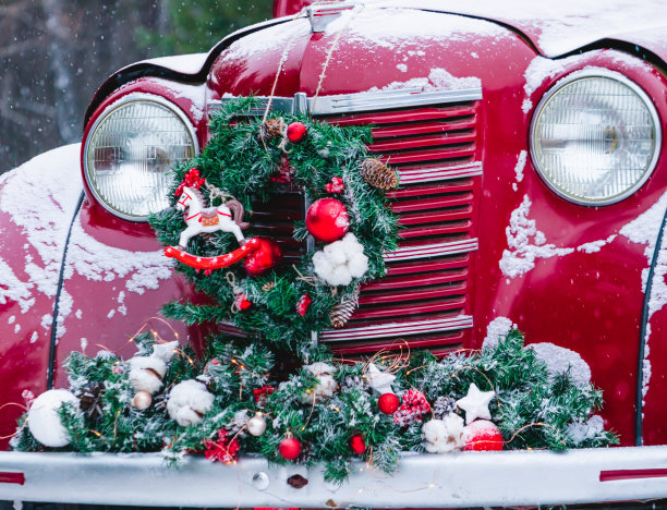 一辆挂着圣诞装饰的红色汽车和圣诞树矗立在白雪覆盖的冬日森林里。喜庆新年概念。图片下载