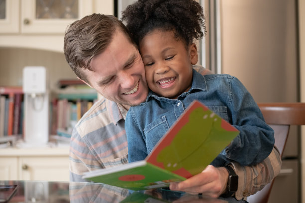 父亲和女儿一起大笑和阅读的照片图片下载