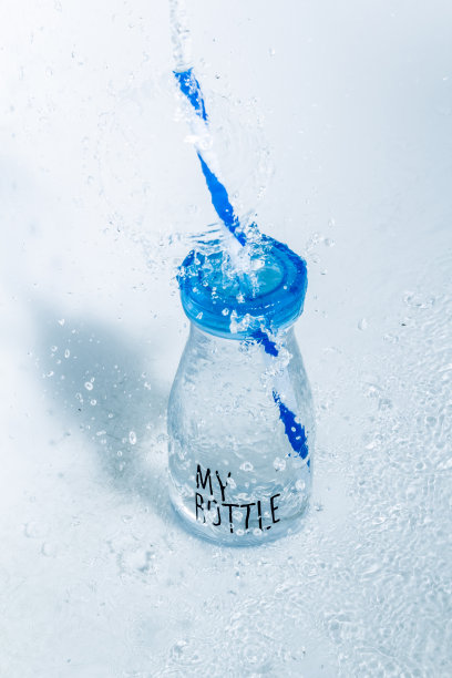 我的水瓶，一个蓝色的盖子和蓝色的吸管与水溅在一个明亮的背景图片下载