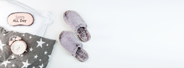 平躺着，穿着灰色的毛绒拖鞋，枕头，眼罩和粉色的闹钟孤立在白色的背景上。顶视图，开销，模型，模板，复制空间。时间休息图片下载