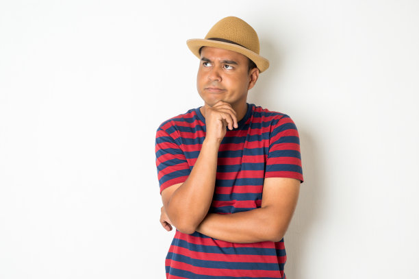 27-35岁左右的亚洲男人正在思考，做着鬼脸，困惑，不理解，对一些事情感到疑惑。这张照片是在照相馆拍的。白色背景图片下载