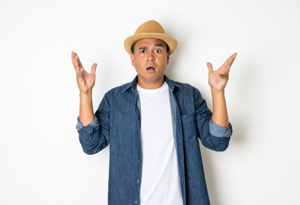 27-35岁左右的亚洲男人正在思考，做着鬼脸，困惑，不理解，对一些事情感到疑惑。这张照片是在照相馆拍的。他穿着一件白衬衫和一件牛仔衬衫。图片下载