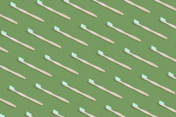 牙刷平放在绿色的背景上。图片下载