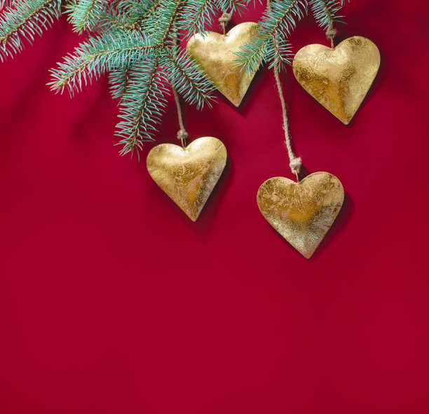 金色的金属心，圣诞玩具，挂在云杉树枝上。圣诞节的照片。图片下载