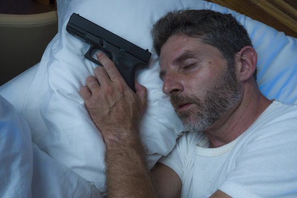 晚上的肖像年轻的压力和偏执的美国男人在床上睡觉和拿着枪害怕闯入家的多疑和自我防卫的概念图片下载