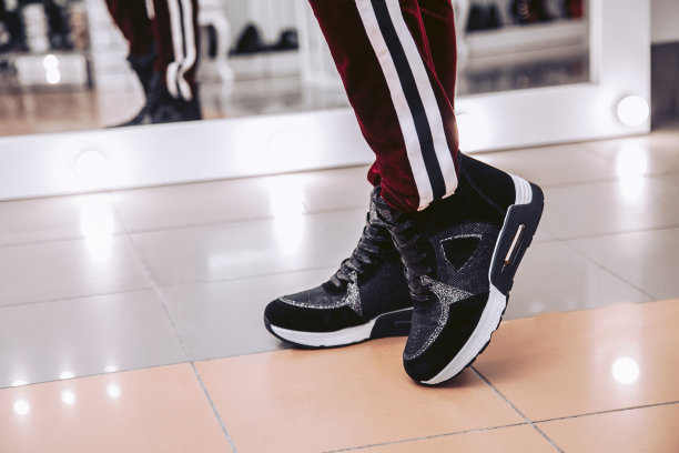 那女孩在鞋店的镜子前擦黑运动鞋。图片下载