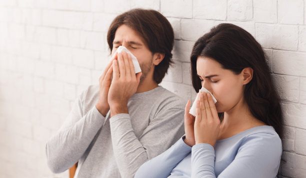 一对年轻夫妇一起生病，在室内用纸巾擤鼻子图片下载