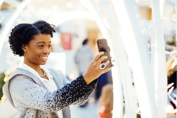 非裔美国妇女在购物中心发短信和自拍，同时准备假期图片下载