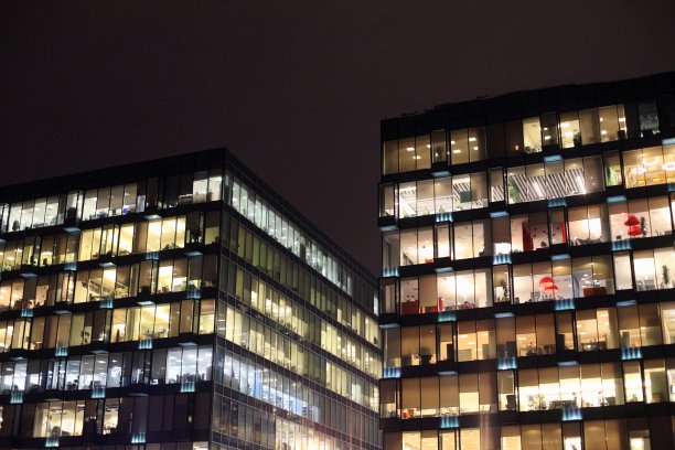 办公大楼在晚上燃烧的窗户。办公室里人们的工作。城市夜景观图片下载