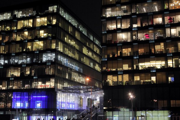 办公大楼在晚上燃烧的窗户。办公室里人们的工作。城市夜景观图片下载