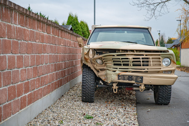 一辆被撞坏的汽车在村里的砖墙附近等待修理图片下载