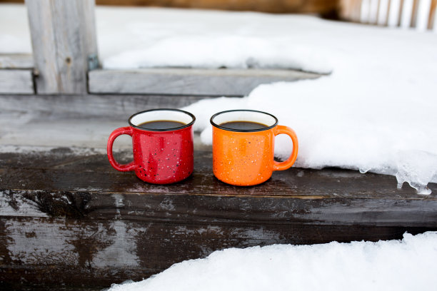 两个咖啡杯放在木屋的门廊上。图片下载