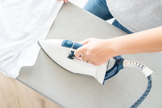 女性双手在熨衣板上熨烫白衬衫的俯视图图片下载