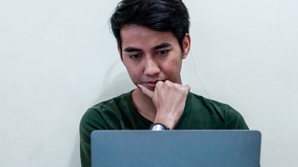 亚洲千禧一代在家工作，一边思考一边看笔记本电脑库存照片图片下载