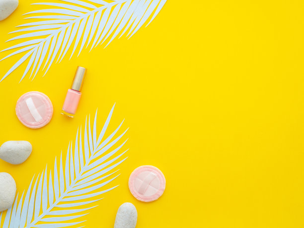 粉沫，米色指甲油，温泉石，两片白色蕨叶孤立在黄色背景。图片下载