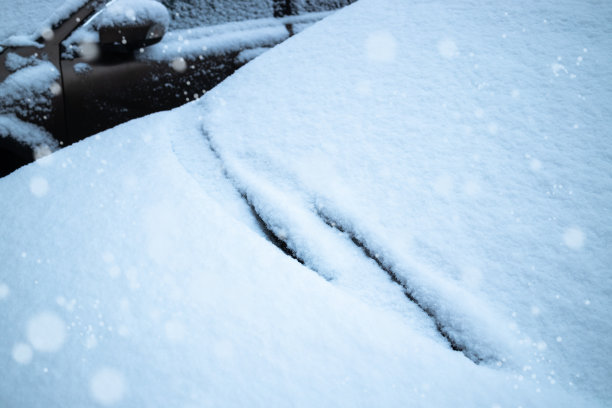 汽车玻璃和清洁刷上覆盖着冰雪。雪落。图片下载