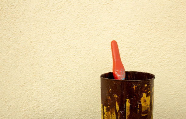 一个用过的油漆锡和刷子反对黄色的墙壁背景图片下载