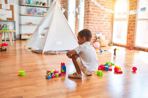 美丽的非洲裔美国学步儿童玩的积木火车玩具在幼儿园的许多玩具图片下载