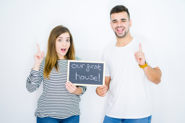 一对年轻夫妇举着黑板，上面写着我们的第一个家庭课文，背景是白色的，他们很惊讶地想到了一个想法或问题，用手指着高兴的脸，第一图片下载