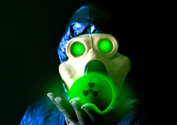 戴着防毒面具的人拿着放射性发光橙色。辐射的影响。环境污染。切尔诺贝利的概念。危险的核电站。图片下载