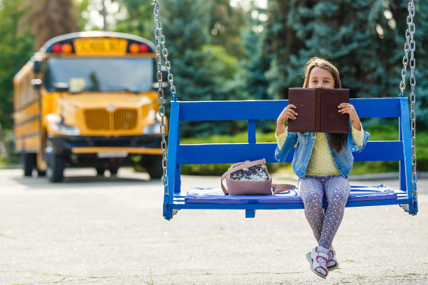 小女孩在学校附近读书。小学生手里拿着书。课的开始。秋天的第一天。图片下载