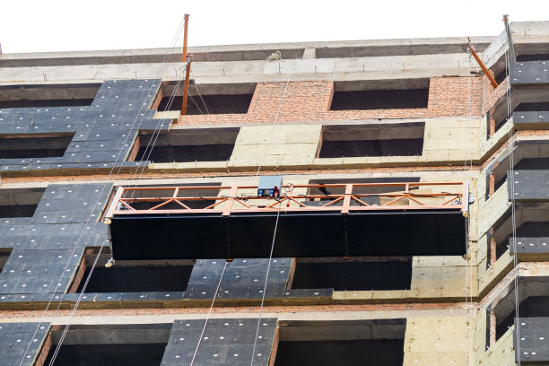 施工现场高塔住宅保温通风外墙上悬挂式施工支架。城市工程背景图片下载