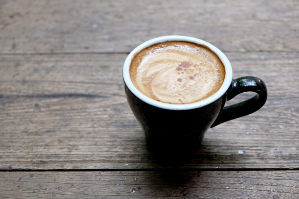 热咖啡杯放在木桌上，以花园为自然背景，清晨雨天的种植园背景——意象图片下载
