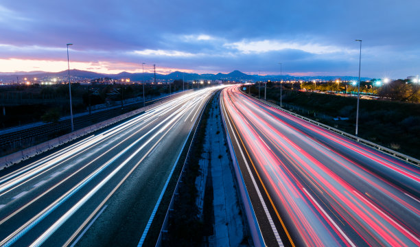 日落时分的高速公路上，车辆朝两个方向行驶，留下了灯光痕迹图片下载