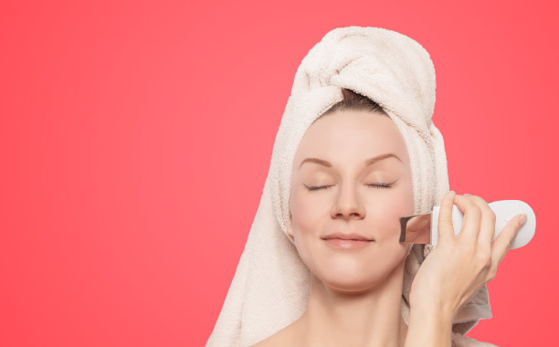 年轻美丽的女人与愉快治疗皮肤与美容装置。女性面部皮肤护理理念图片下载