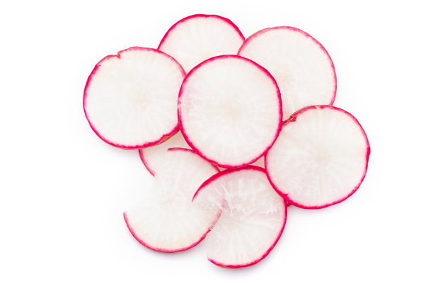 块茎粉萝卜切成片，堆在一起在白色的背景。图片下载