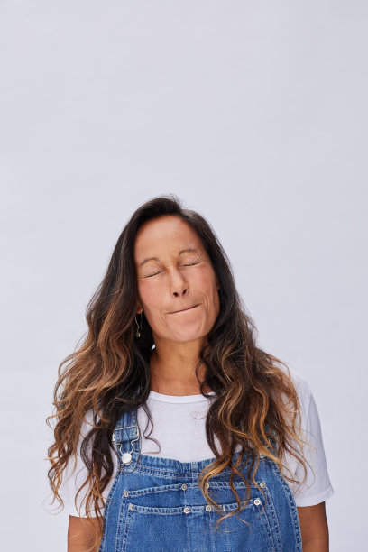 在灰色的背景下闭着眼睛，撅着嘴的女人图片下载