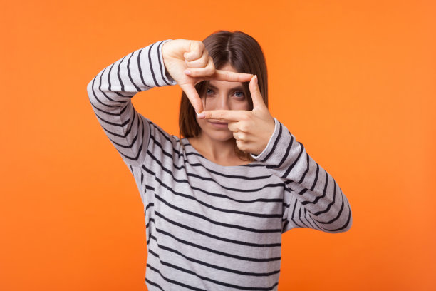 棕色头发的创意女性肖像，身穿长袖衬衫，橙色背景室内工作室拍摄图片下载