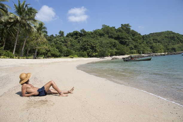 一名皮肤黝黑、头戴草帽的男子躺在空荡荡的缅甸海滩上图片下载