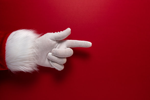 圣诞老人戴着手套的手是指着的手势。圣诞节或新年的最小概念。图片下载