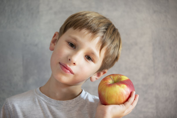 孩子与水果。拿着大苹果的有趣男孩图片下载