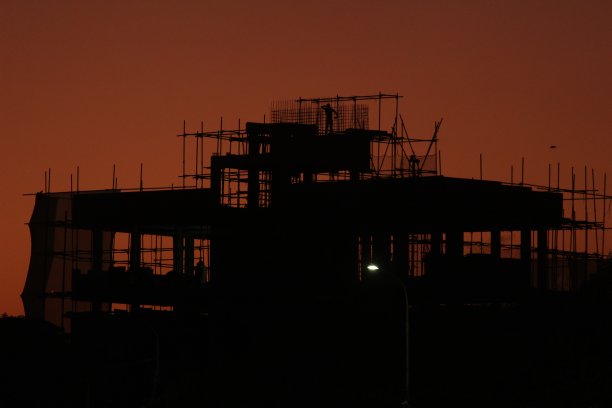 夕阳西下后，建筑工人在建筑工地施工的剪影。高地和安全概念。图片下载