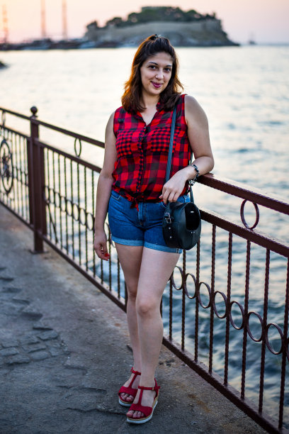 一幅美丽的年轻女孩的肖像，她倚在海岸线的栏杆上，身后是一个小岛图片下载