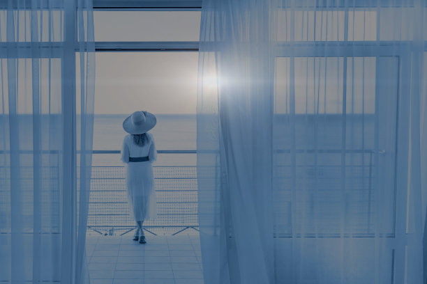 在初夏的早晨，一个女人在阳台上欣赏着美丽的海景。图片下载